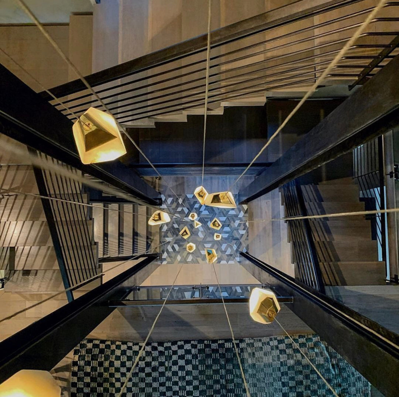 Alabaster lights in this interior space hanging down the middle of this staircase give a warm glow and art as people ascend and decent the home's floors.