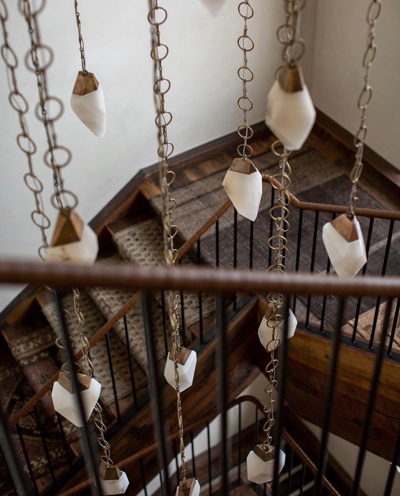 Fathom Stone Art alabaster lighting collection by Randy Zieber have many hanging options including these stylized custom chains flowing down this staircase.