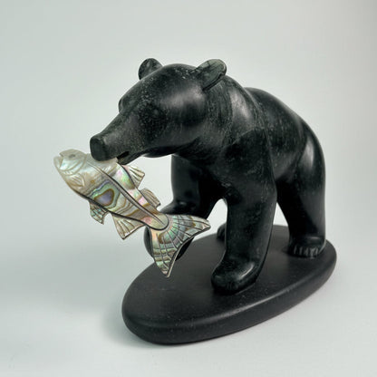 Stone sculpture of a bear holding a fish against a white background