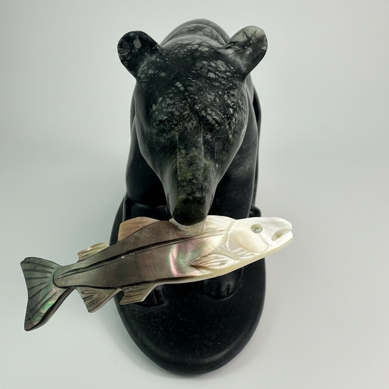Carved stone bear holding a fish on a white background