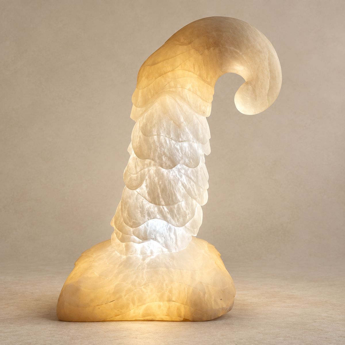 A sculptural alabaster amp shaped like a tall, curled wizard hat made from layered translucent material that glows warm yellow from within, set against a plain beige studio background.