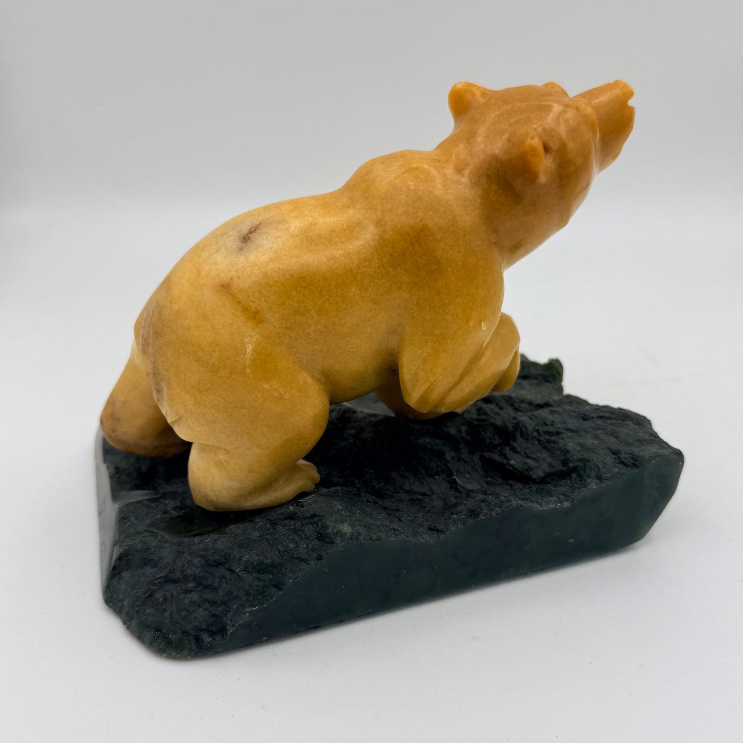 Bear sculpture on a green jade base against a white background