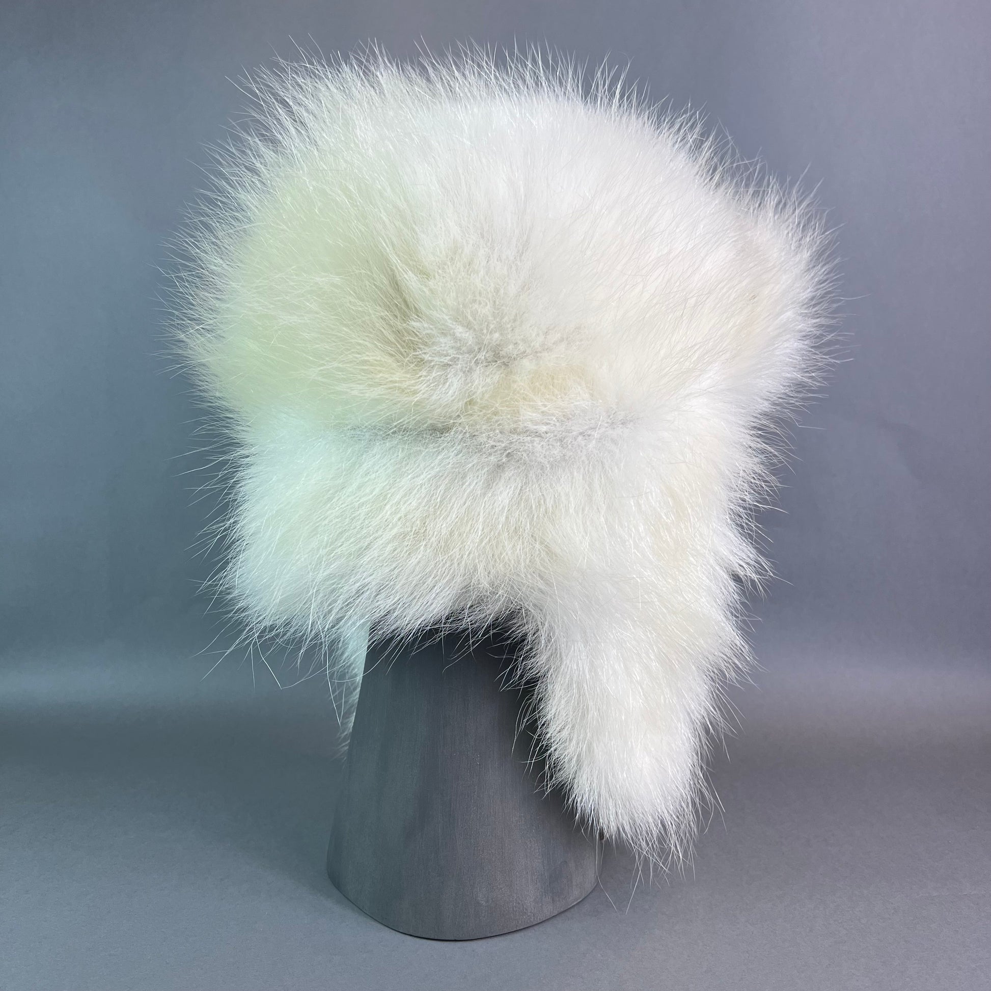 White fur hat on a gray mannequin head against a gray background
