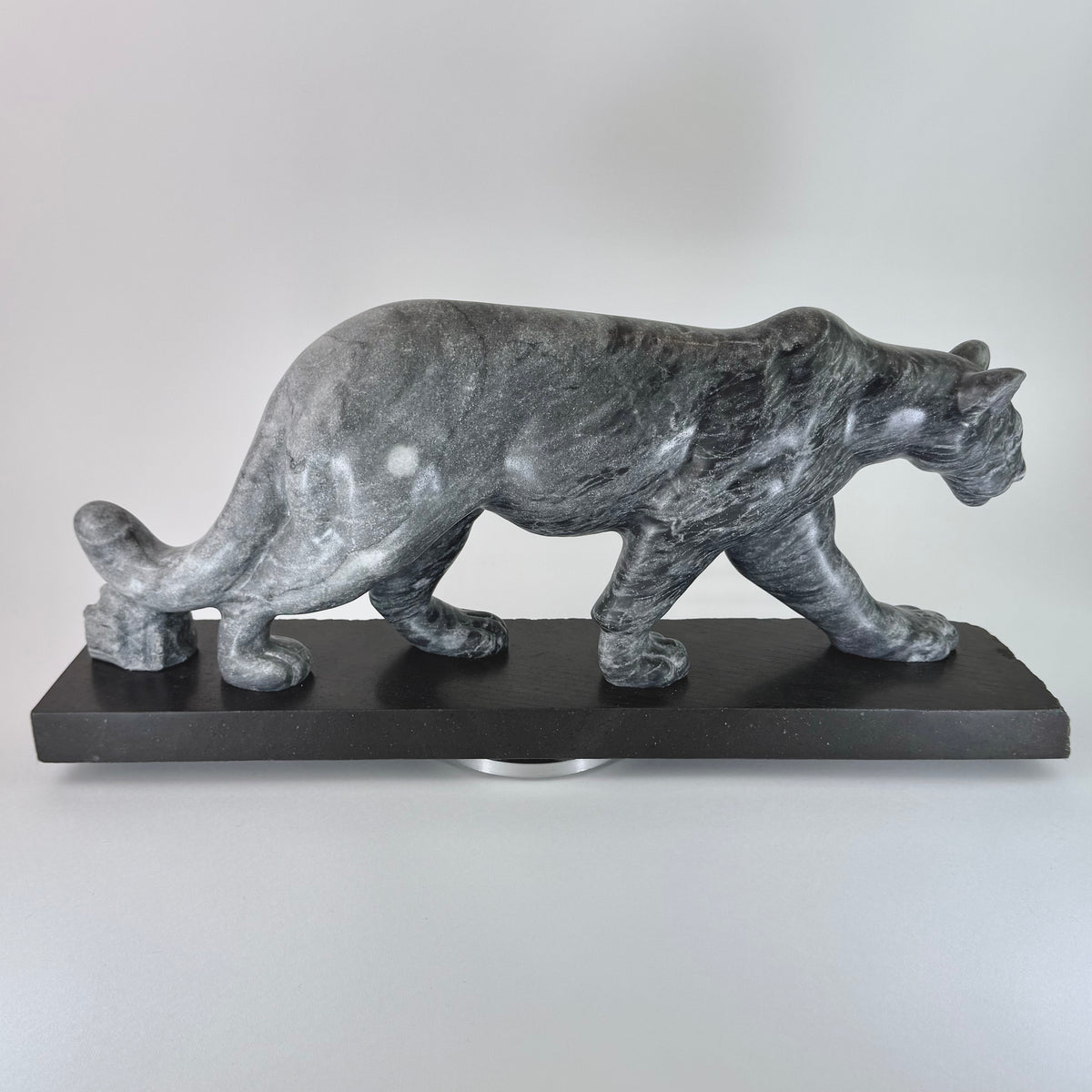 Gray marble sculpture of a panther on a black base against a white background