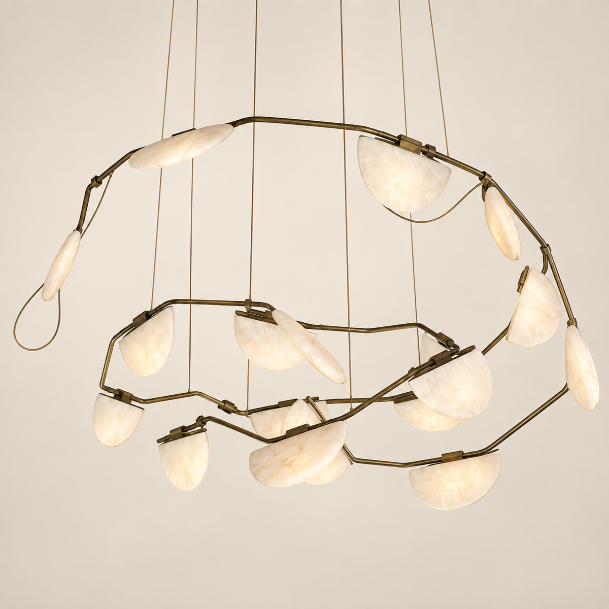 A modern spiral alabaster stone chandelier with a dark brass metal frame and multiple curved, semi-circular off-white glass shades suspended by thin cords against a plain light beige background.