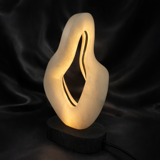 Hand-carved abstract alabaster LED lamp glowing with warm light at Fathom Stone Art Gallery Whistler.
