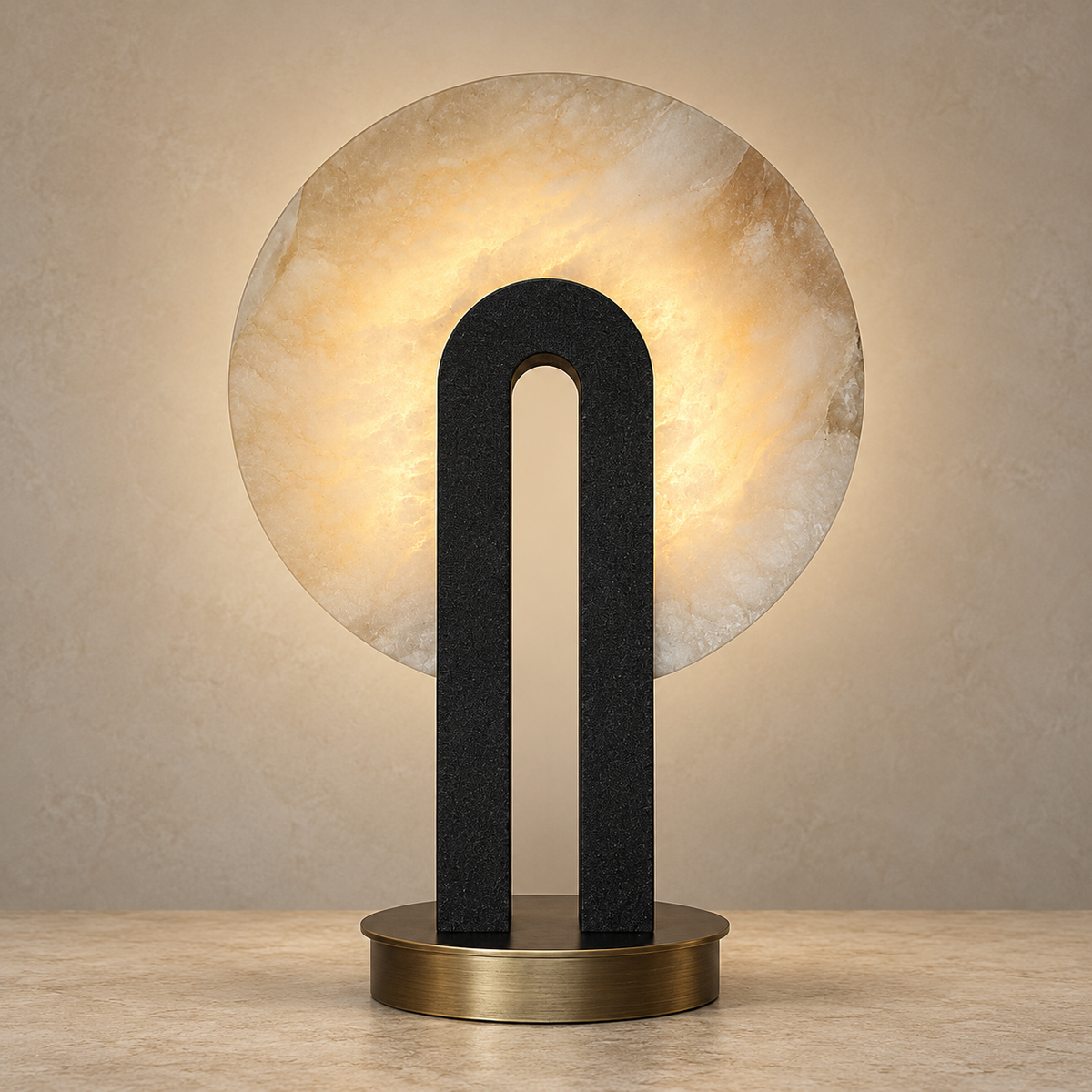 A modern table lamp featuring a large circular warm-white stone shade, a matte black U-shaped central column, and a round brushed brass base, set against a textured beige wall.