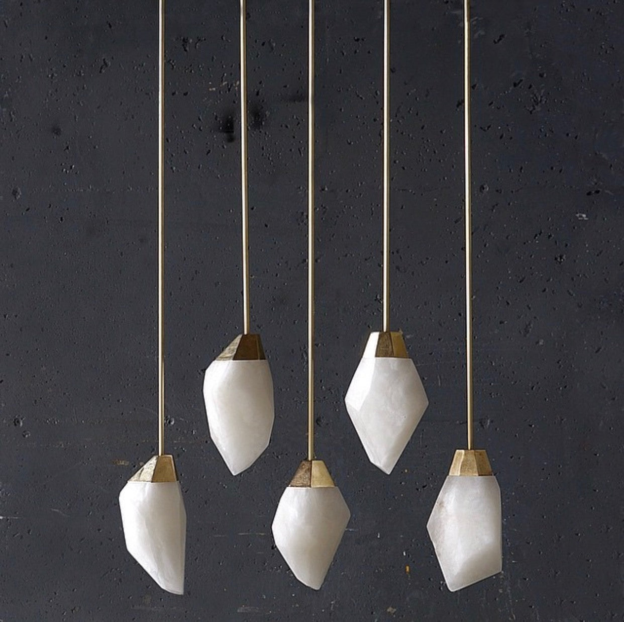 These alabaster faceted pendant lights have polished brass tops and are hung from brass pipes.