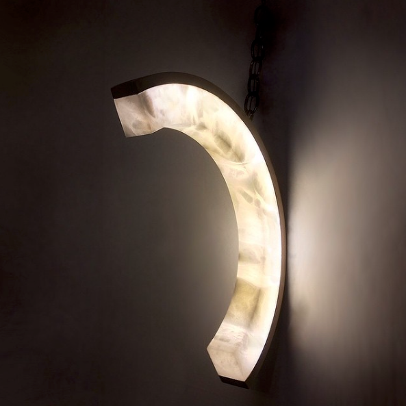 This soft cornered alabaster C lights hung on a chain on the wall glows and shows the natural veining and patterns in the stone.  The precision cut on this alabaster  in perfectly inlayed to the brass metal backing.  Fathom Stone Art Lighting.