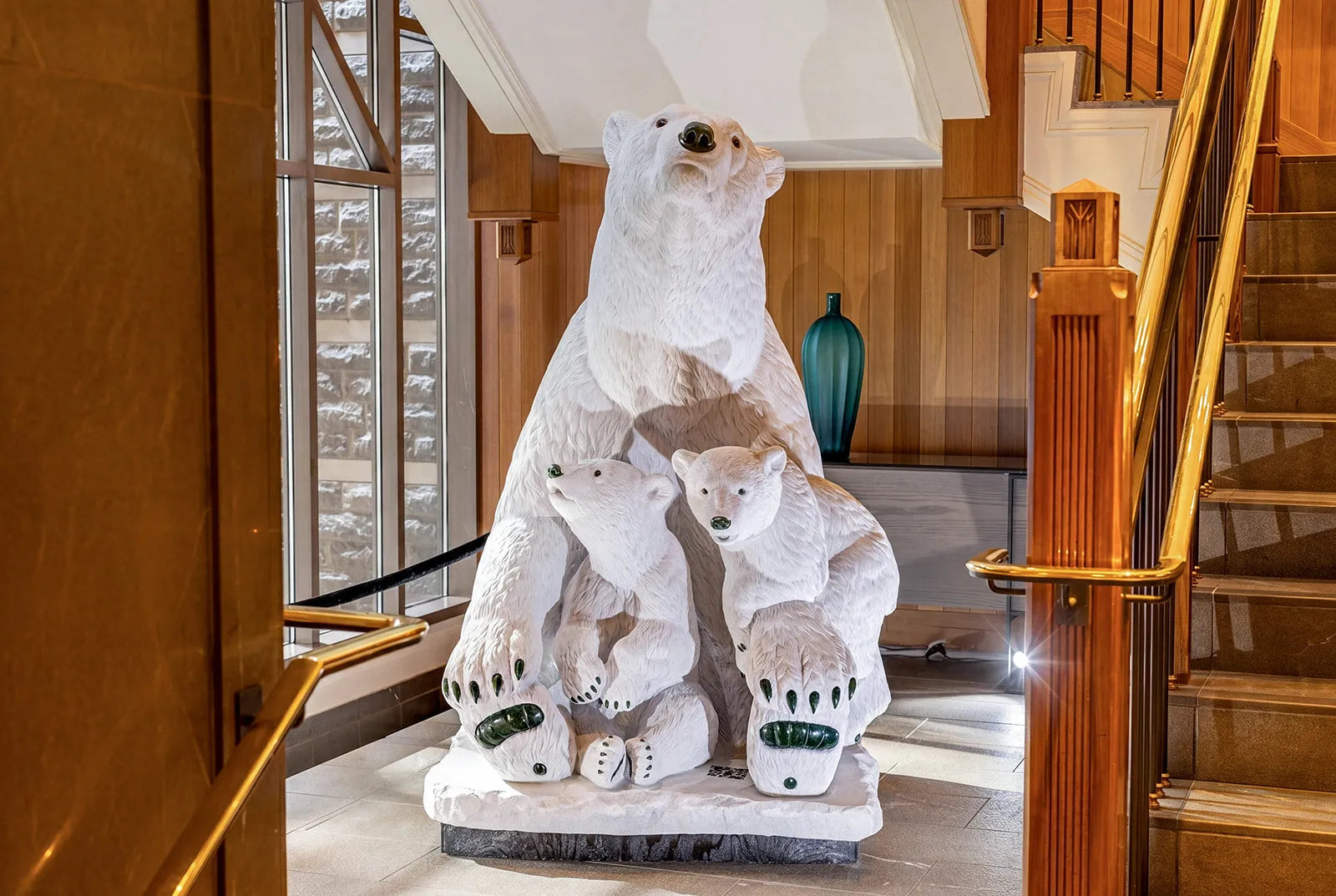 Borealis, a life-size white marble polar bear with two cubs, installed in a timber-clad resort lobby