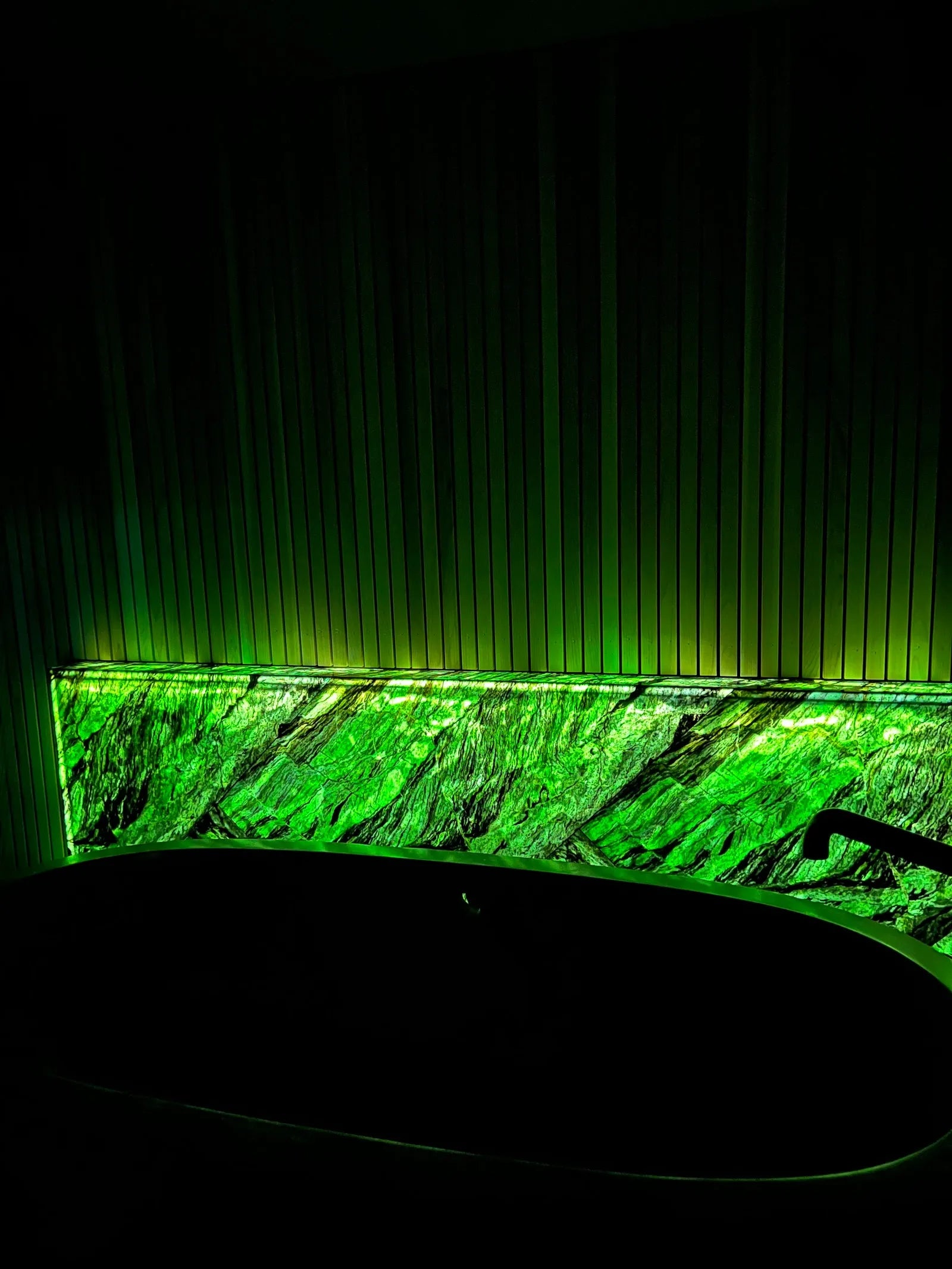 Glowing Jade, a backlit bar front of translucent green BC jade in a dark room